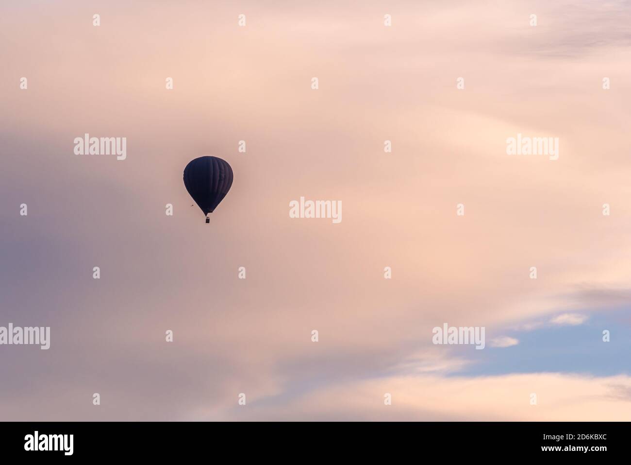 Aerostatic balloon flying over a colorful sky at dawn Stock Photo