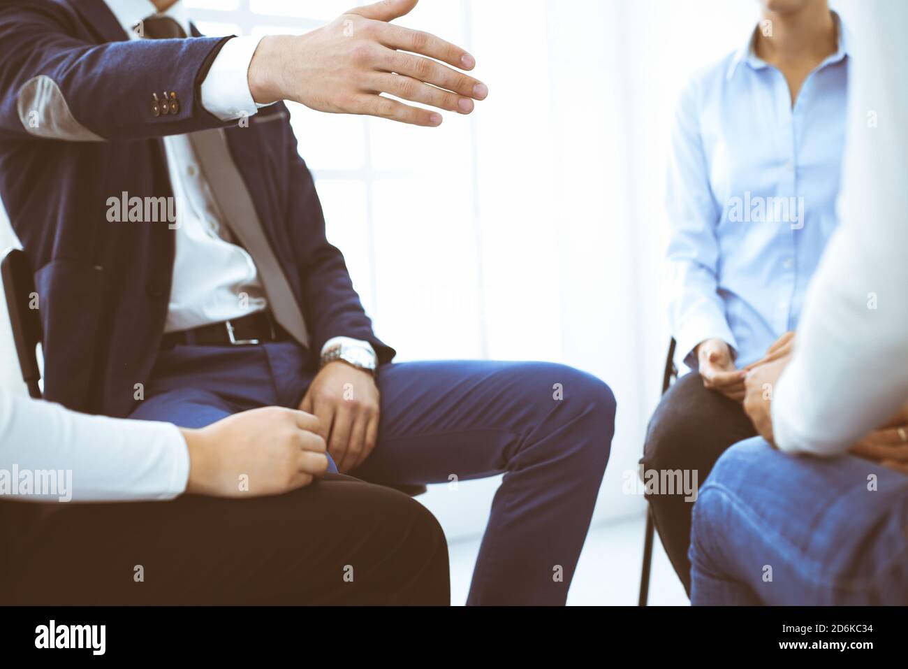 Group of people sitting in a circle during therapy in office. Meeting of business team participating in training Stock Photo