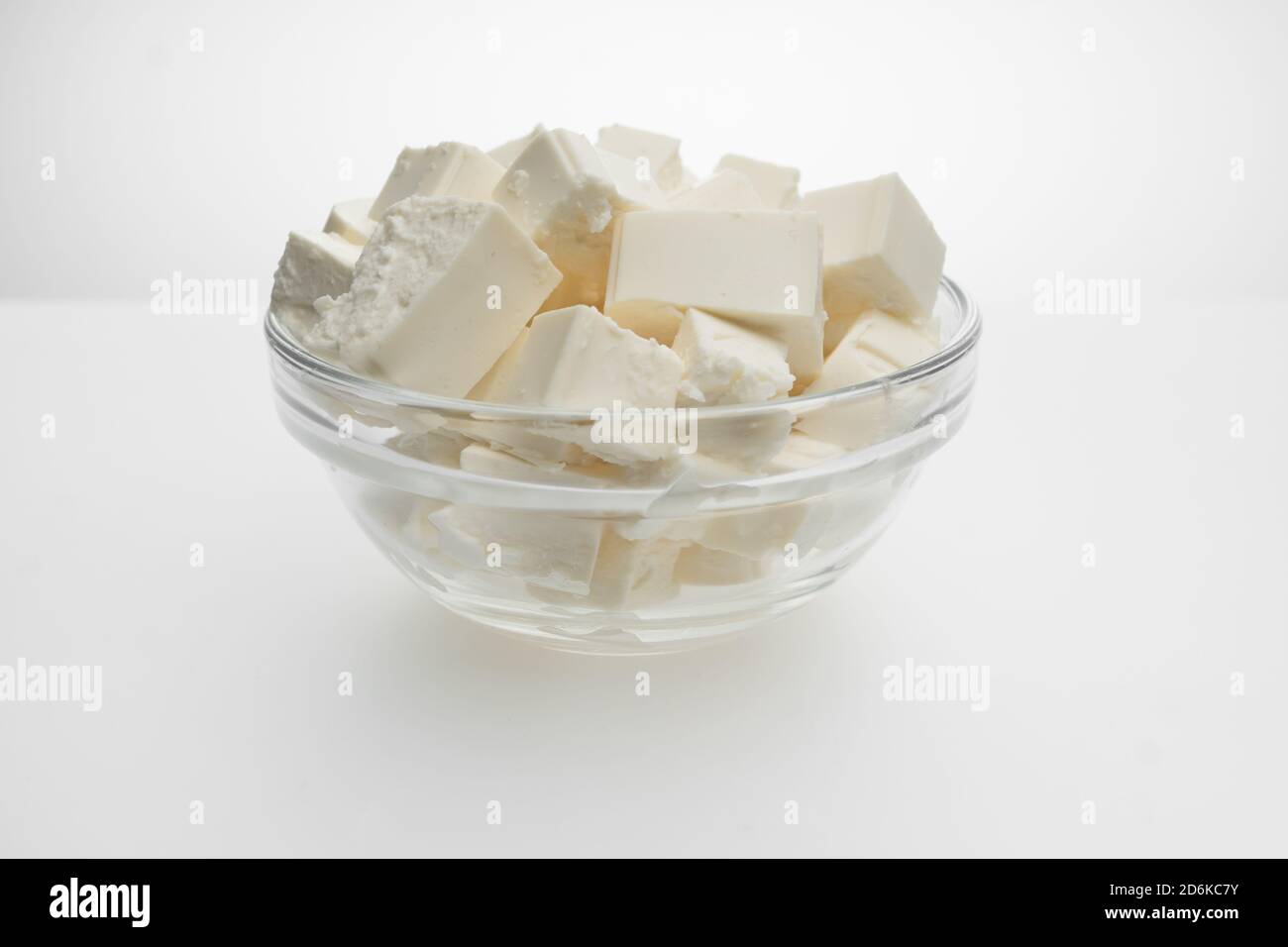 Feta cheese closeup cut into cubes in a transparent bowl, top view