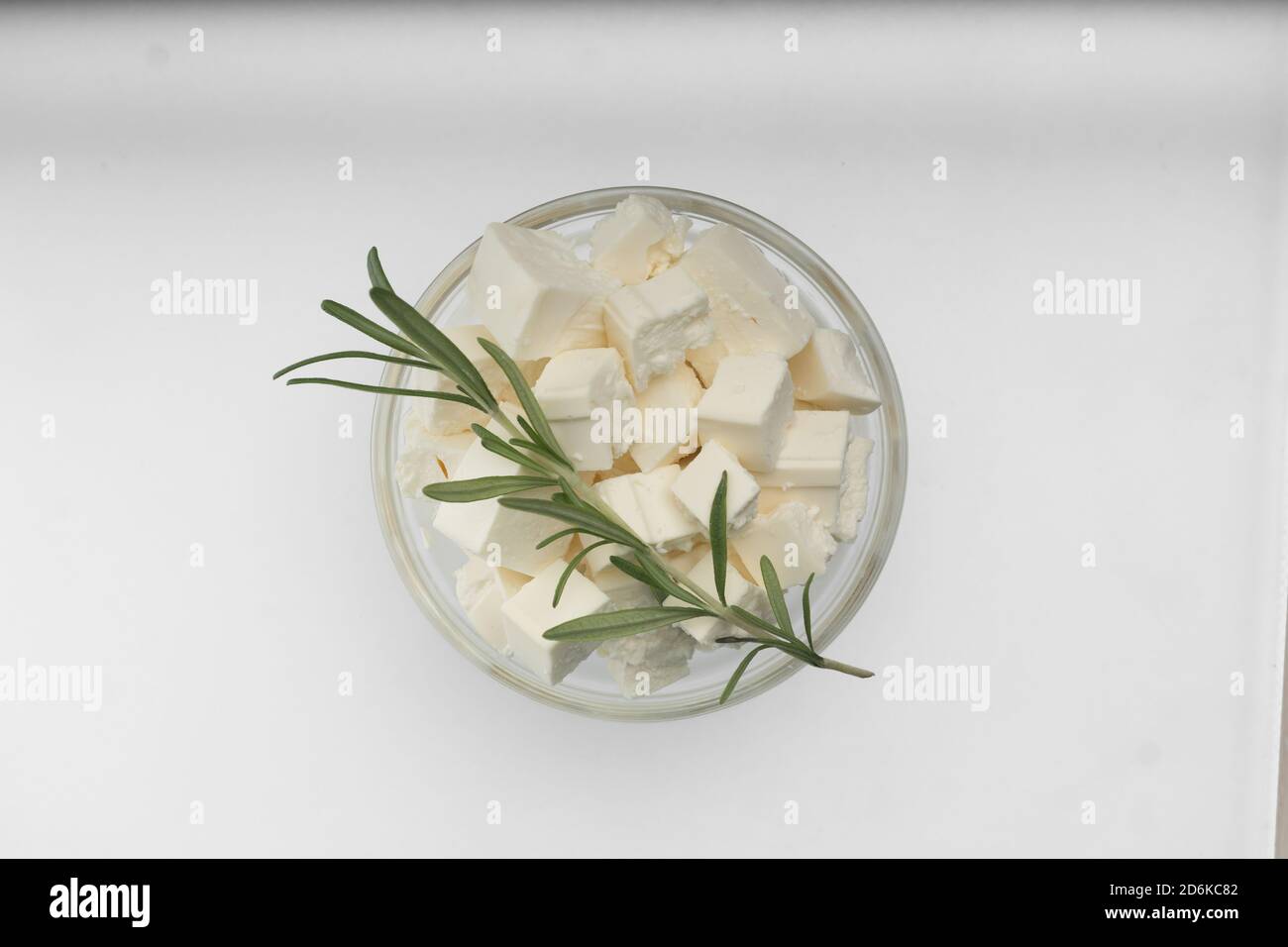 Feta cheese closeup cut into cubes in a transparent bowl, top view