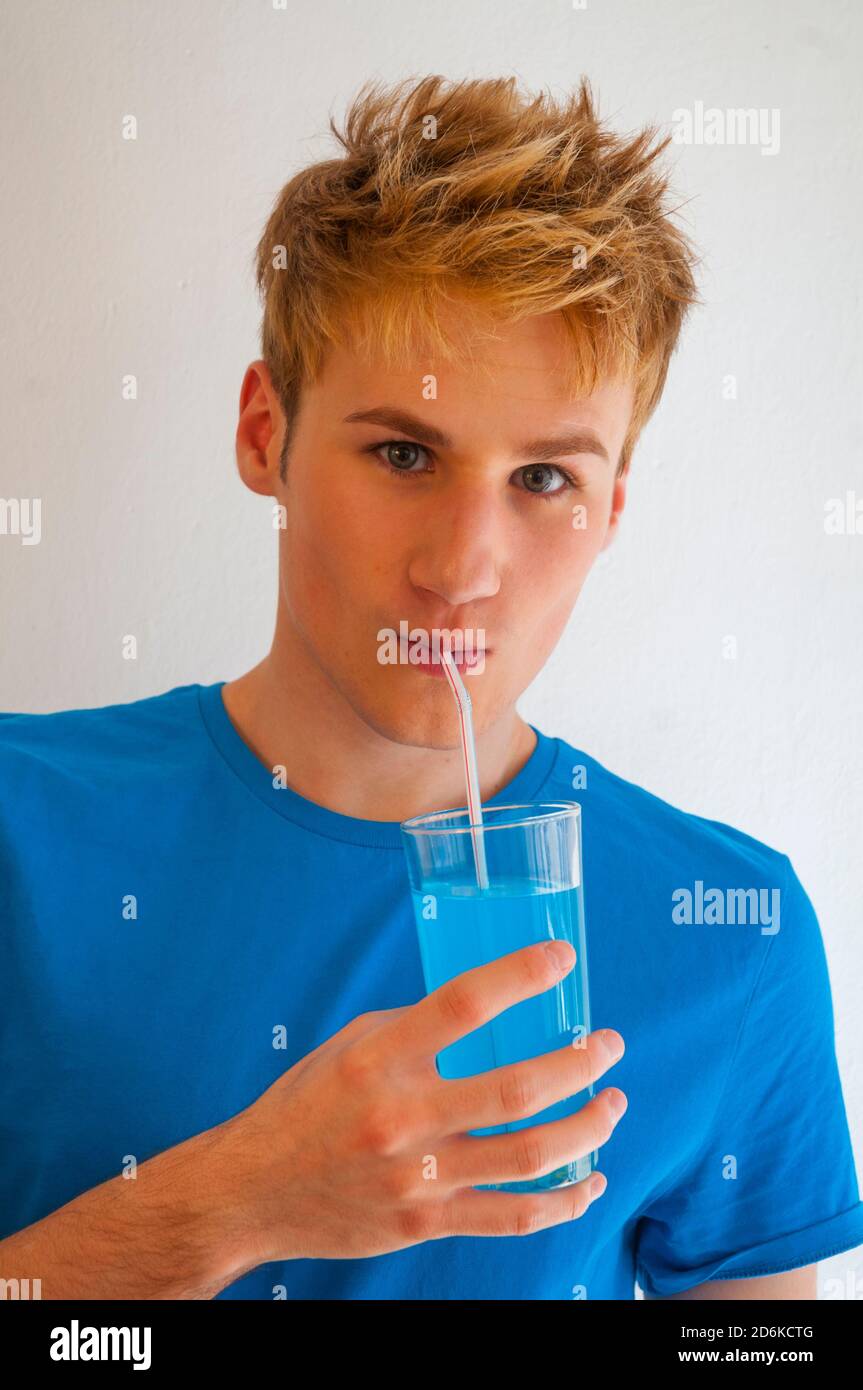 Young man wearing blue T-shirt and drinking blue soft drink. Stock Photo