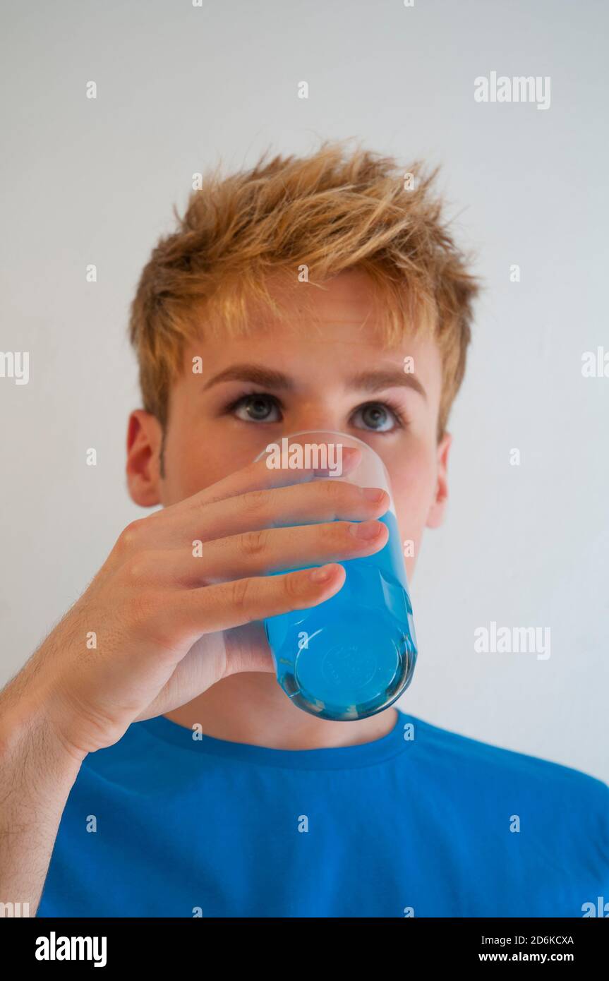 Young man wearing blue T-shirt and drinking blue soft drink. Stock Photo