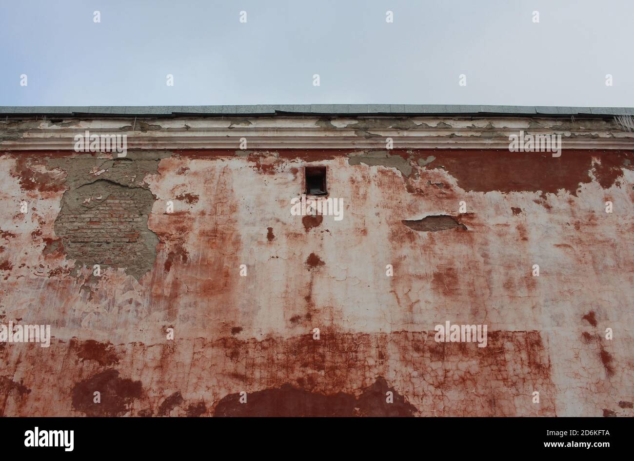 the old ruined wall of a brick building with a viewing window crumbled ...