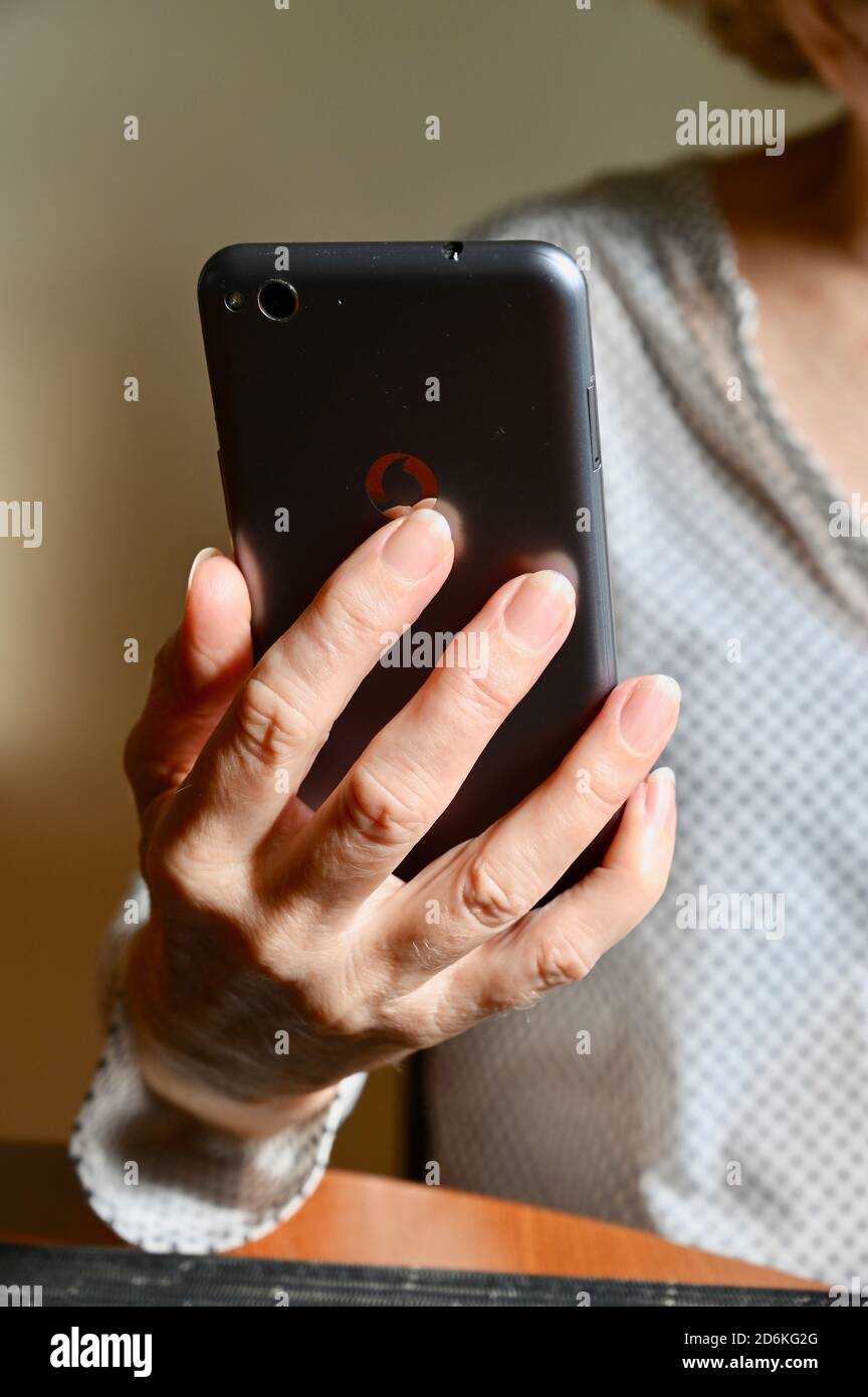 Close-up of a senior woman using a Vodafone mobile phone. Stock Photo