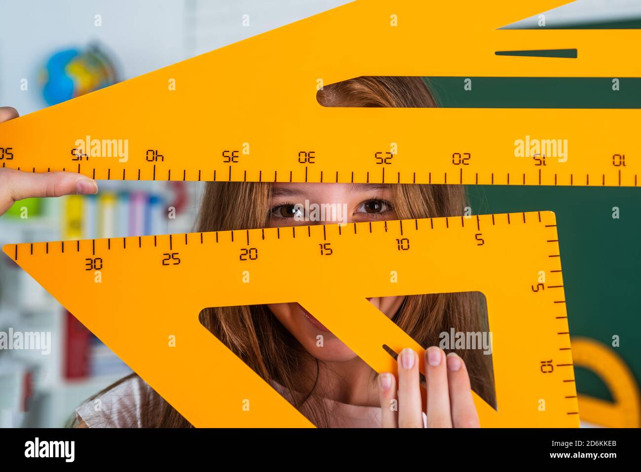 cheerful girl work in school classroom with math triangle tool ruler ...