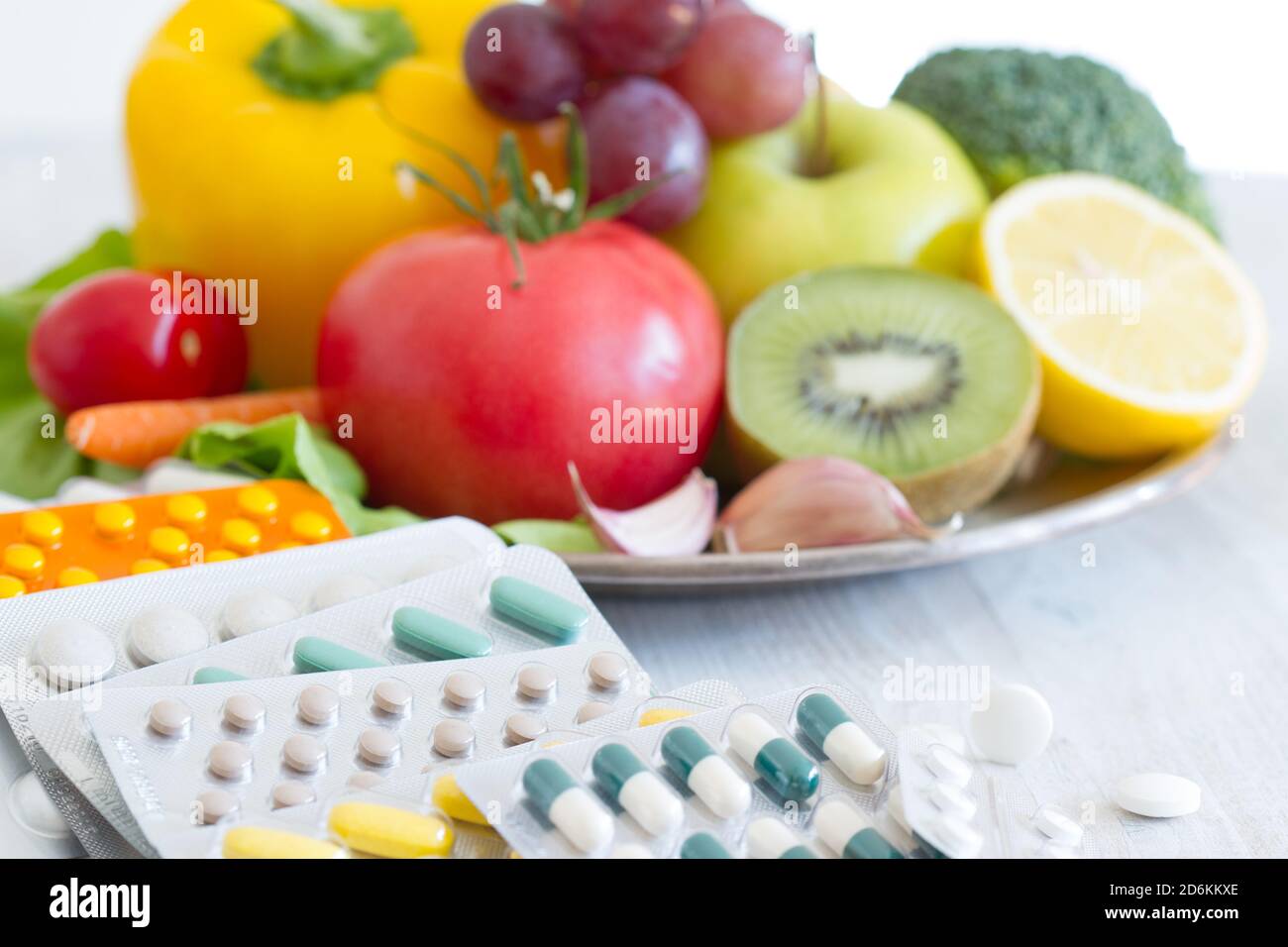 Fruits and vegetables platter, medications in background. Healthy diet