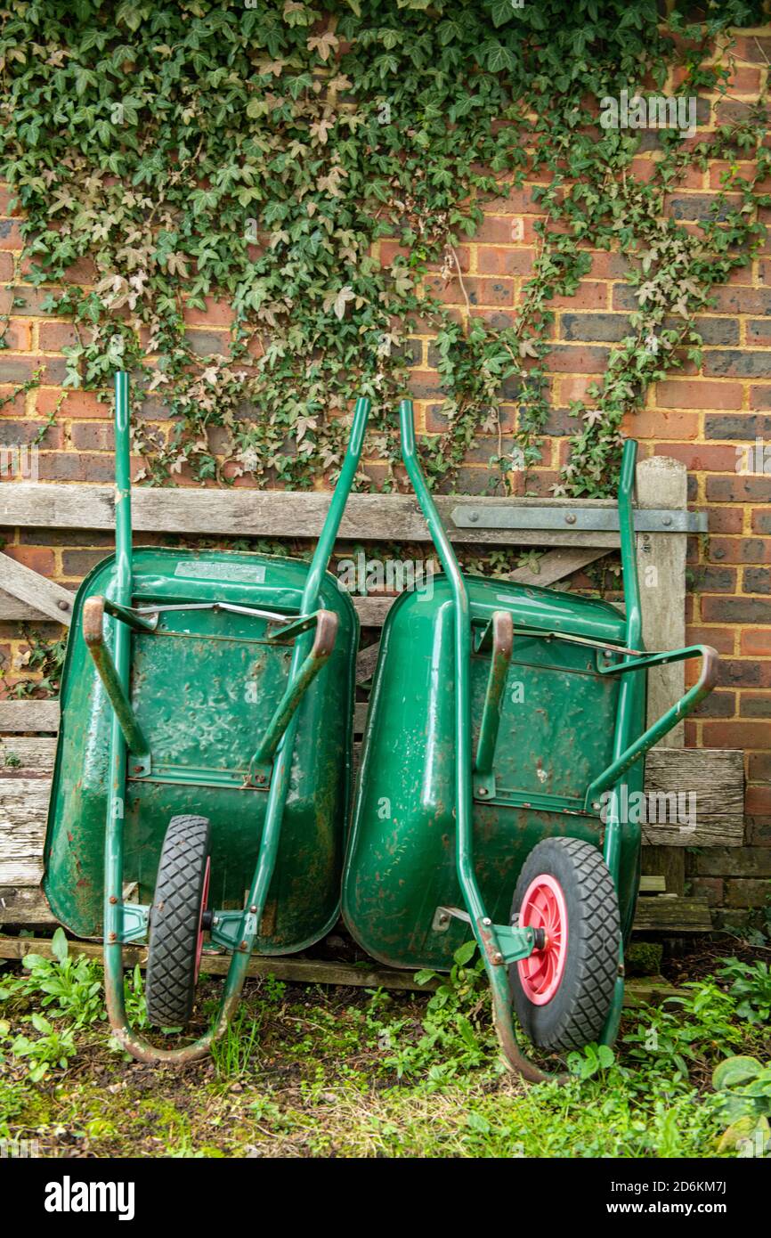 Two wheelbarrows leaning against a garden wall Stock Photo Alamy