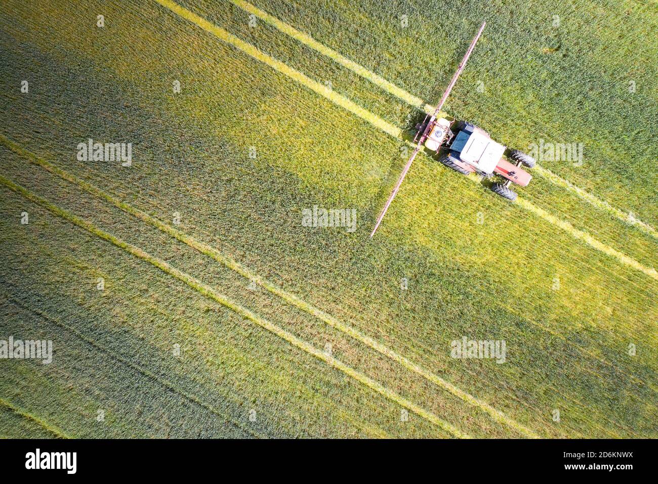 Drone point of view of a Tractor spraying on a cultivated field. Stock Photo