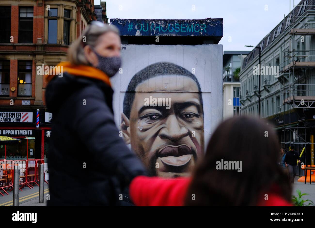 Manchester / United Kingdom - October 17, 2020: Manchester’s George Floyd mural seen through blurred couple of people passing by it Stock Photo