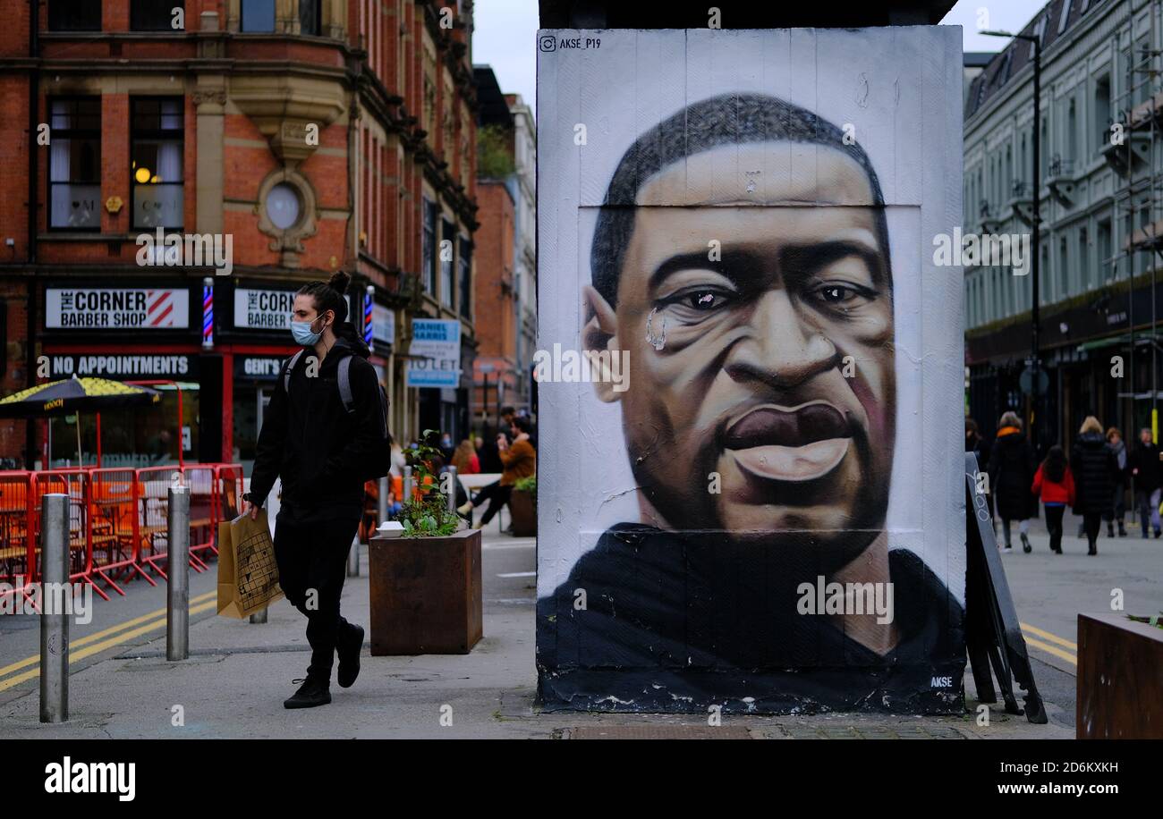 Manchester / United Kingdom - October 17, 2020: Manchesters George Floyd mural and young man in medical mask passing by it. Stock Photo