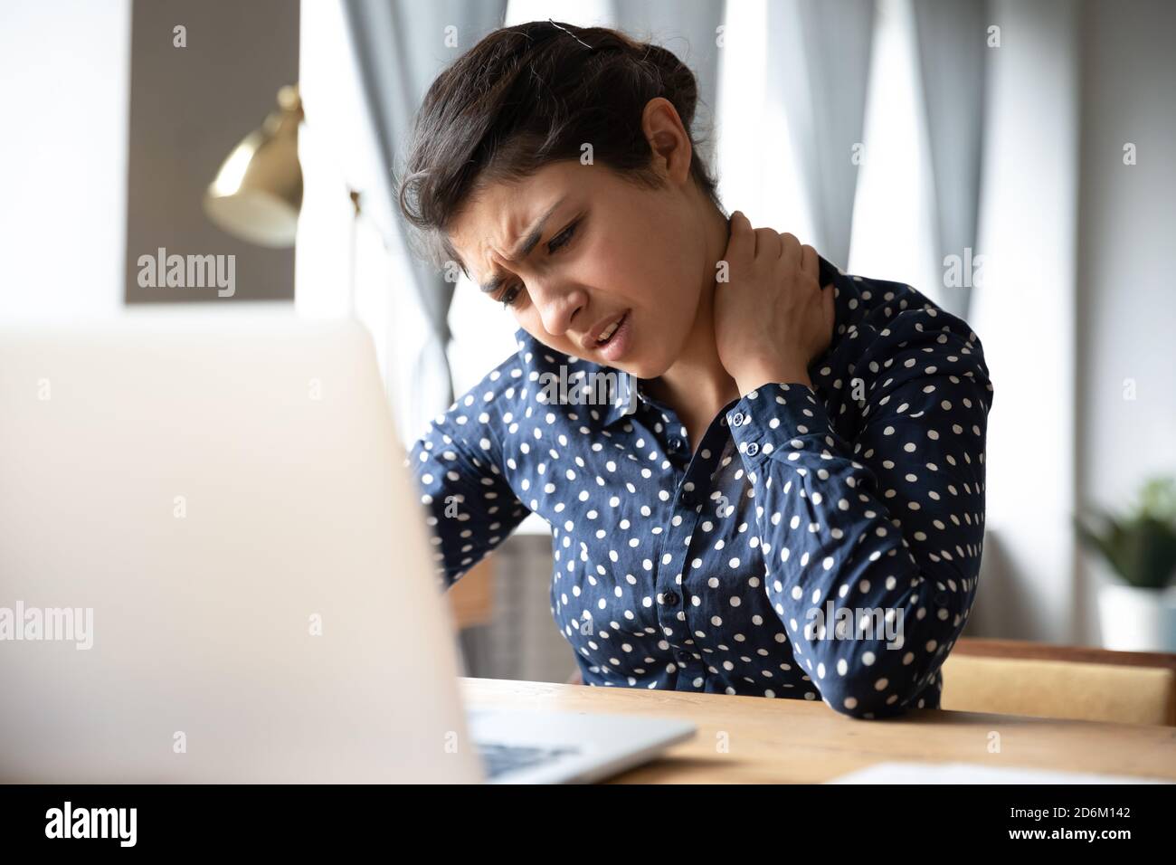 Indian woman sitting at desk touch neck feels pain Stock Photo Alamy