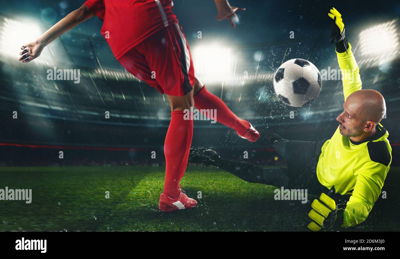 Soccer goalkeeper, in fluorescent uniform, countering the attacker in red uniform Stock Photo