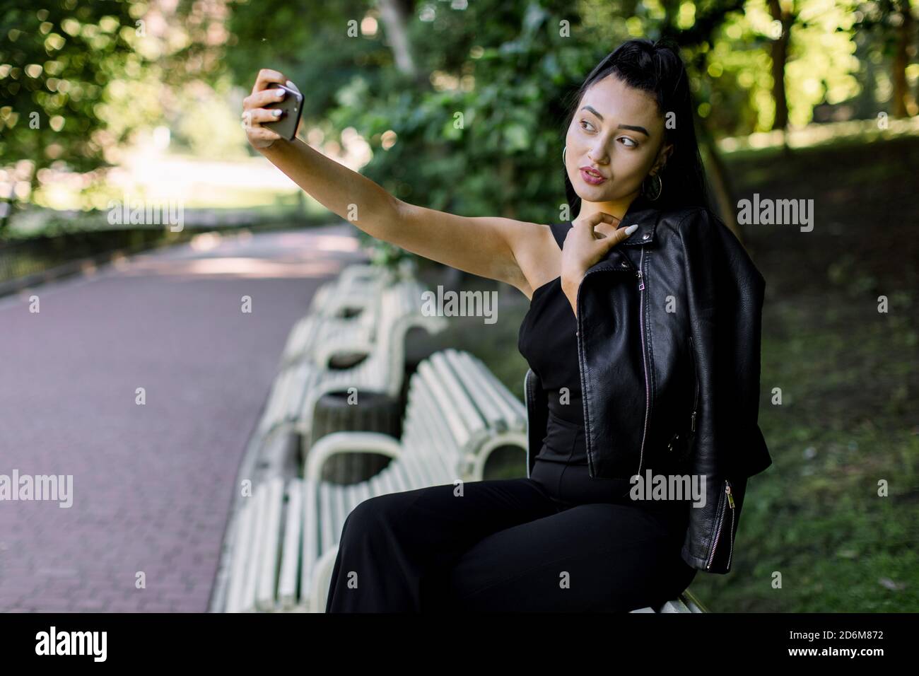 Free Photo  Young stylish woman walking in street in fashionable outfit,  holding purse, wearing black leather jacket and white lace dress, spring  autumn style, posing, high leather boots