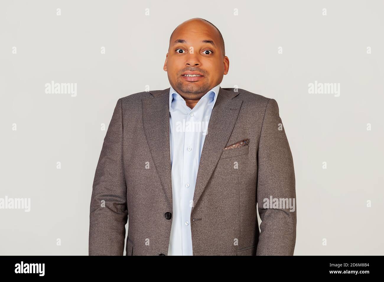 Annoyed African American guy businessman frowns with displeasure, annoyed with bad news, feeling disgusted and displeased, looks excited, gesturing funny and comical. Standing on a gray background Stock Photo