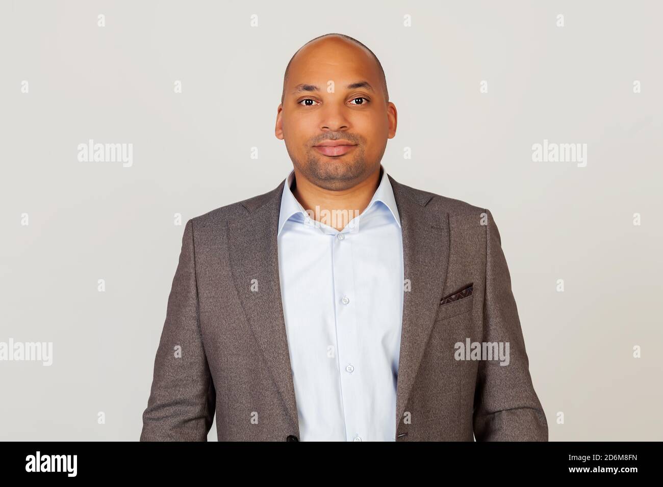 Portrait of a young African American guy businessman smiling and looking at the camera, looking trustworthy and sincere with a friendly kind smile, standing against gray background Stock Photo