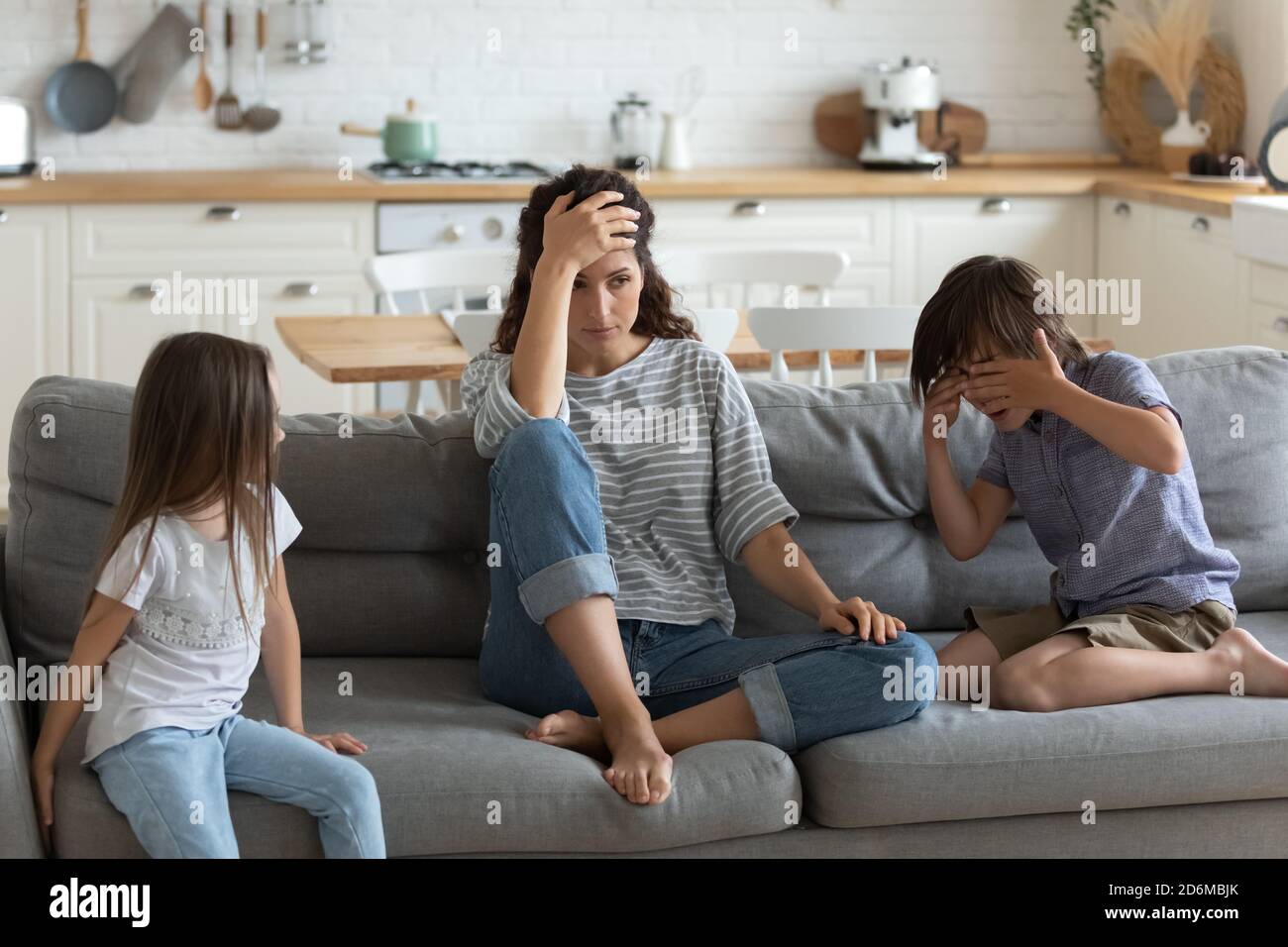 Tired exhausted mother having problem with naughty noisy kids Stock Photo