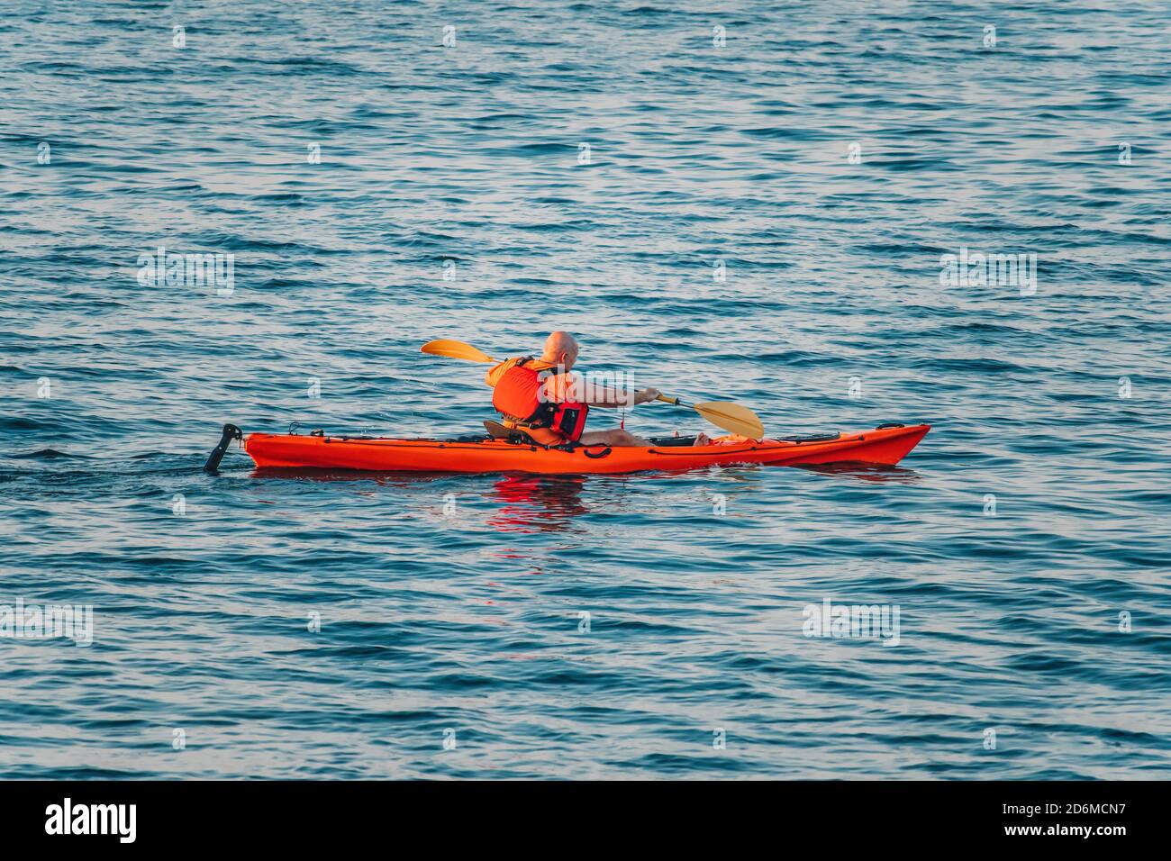 Aged Male kayaker in a red kayak on the background of the sea. Copy space. The concept of travel, relaxation, active and healthy life in harmony with Stock Photo