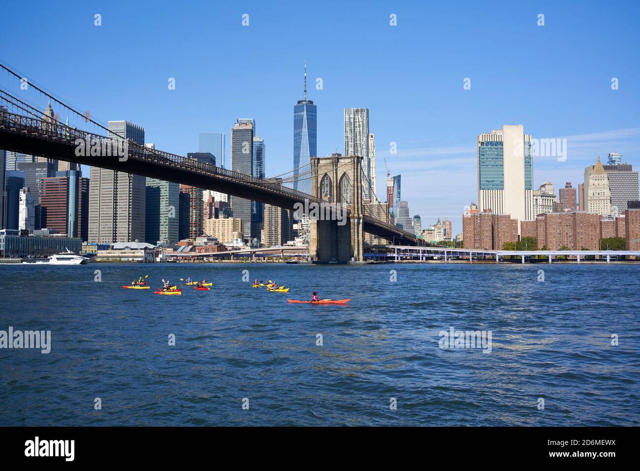 Kayakers kayaking under the Brooklyn Bridge on the East River with New