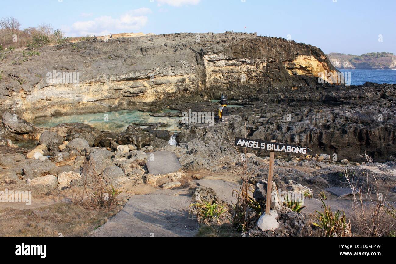Upper part of Angel's Billabong showing sign with upper pool, eroded black rock, cliff and ocean in background in Nusa Penida, Indonesia Stock Photo