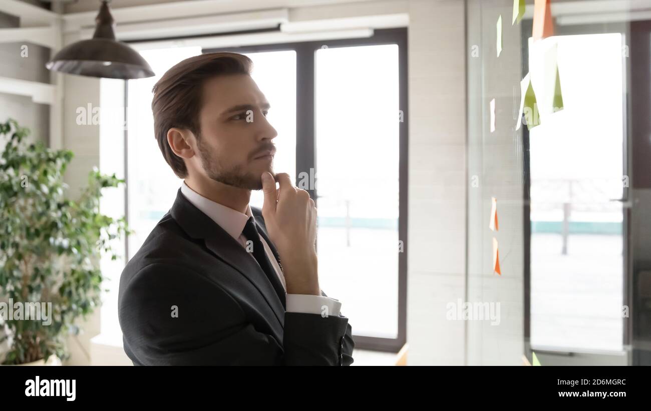 Pensive young corporate employee using project management tool. Stock Photo