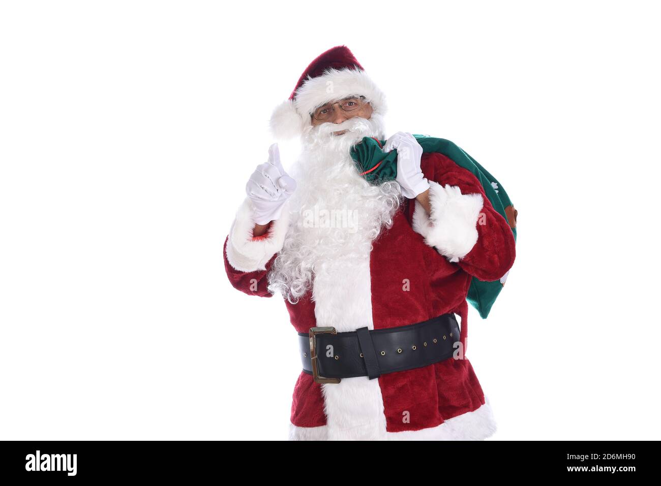 Senior man in traditional Santa Claus costume with a bag of toys over his shoulder and pointg wiht the other hand. Isolated on white. Stock Photo