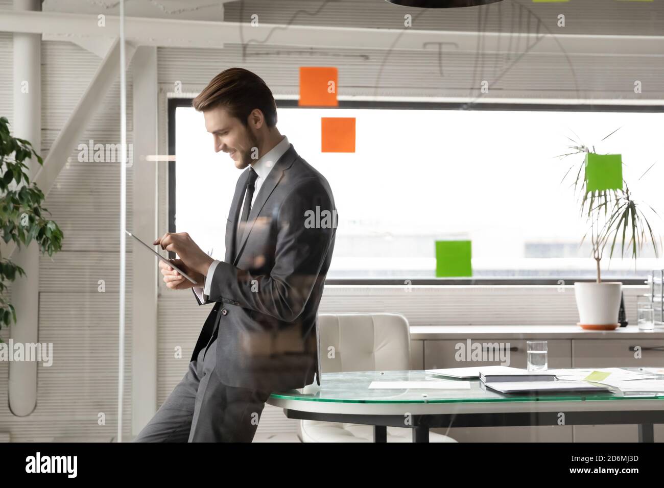 Smiling young businessman using digital computer tablet in office. Stock Photo