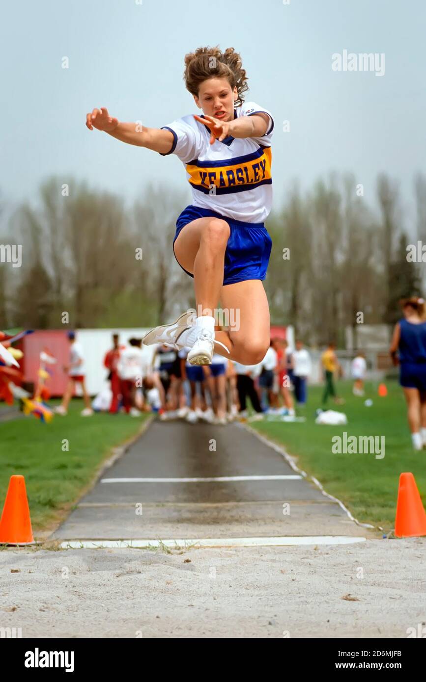 Female competes in the long jump event at a high school track meet Stock Photo