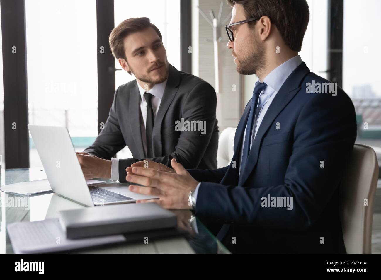 Focused confident two business partners discussing online project computer presentation. Stock Photo