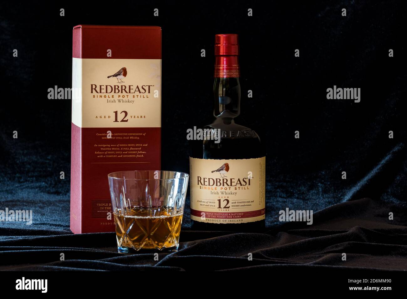 Still life of Redbreast irish whiskey bottle and crsytal whisky tumbler on black velvet background Stock Photo
