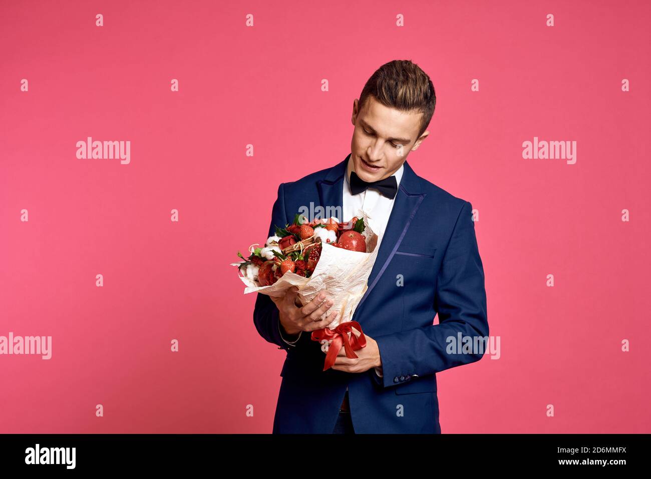 romantic man with bouquet of flowers and in bow tie on pink background ...