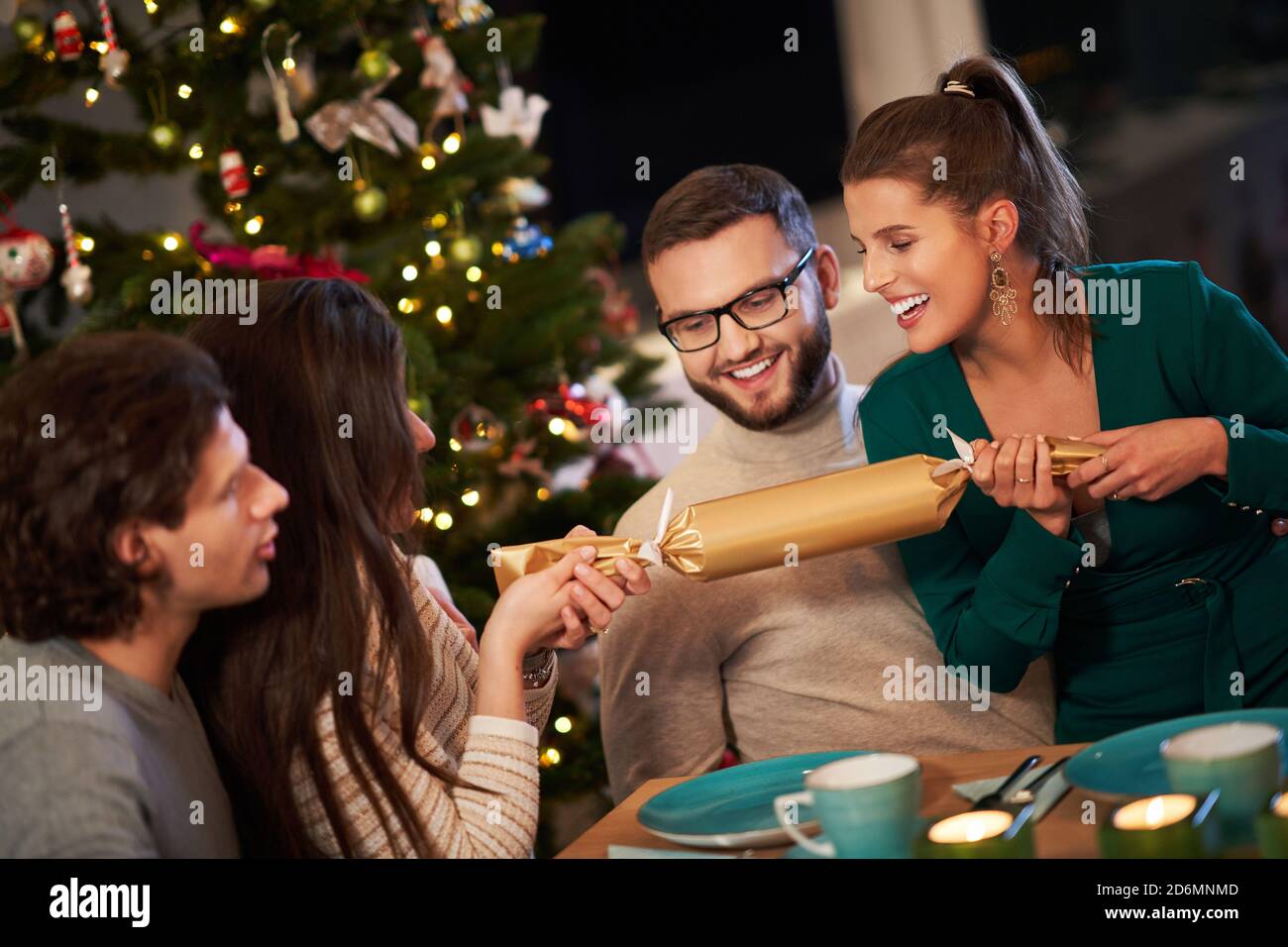 Group of friends celebrating Christmas by pulling crackers Stock Photo