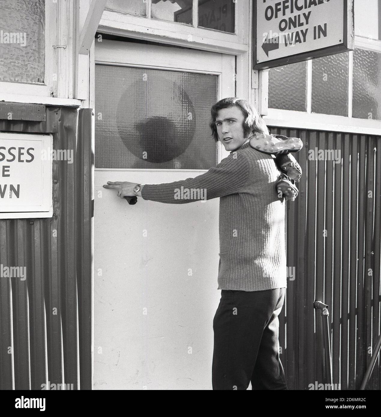 1970s, historical, a footballer of the era, causally dressed and with his boots over his shoulders entering the players and officals entrance to a fooball ground, South East London, England, UK. Stock Photo