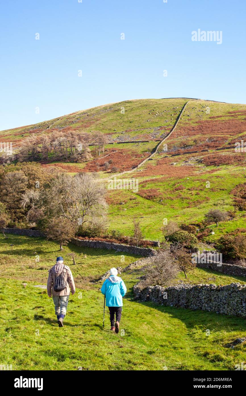 Elderly man and woman couple pensioners senior citizens  walking rambling backpacking in the north Yorkshire Dales in the hills above Kirkby Lonsdale Stock Photo