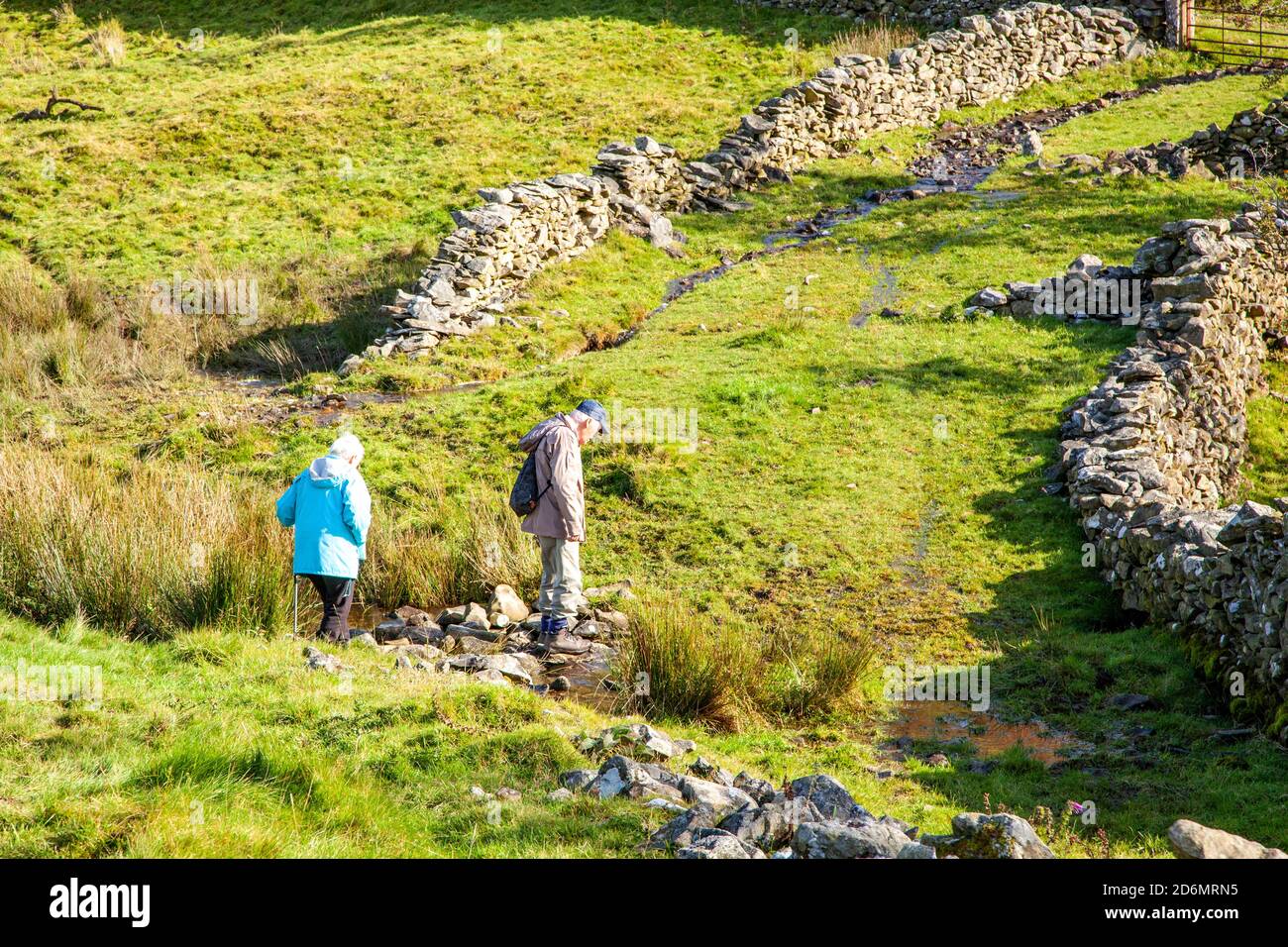 Elderly man and woman couple pensioners senior citizens  walking rambling backpacking in the north Yorkshire Dales in the hills above Kirkby Lonsdale Stock Photo