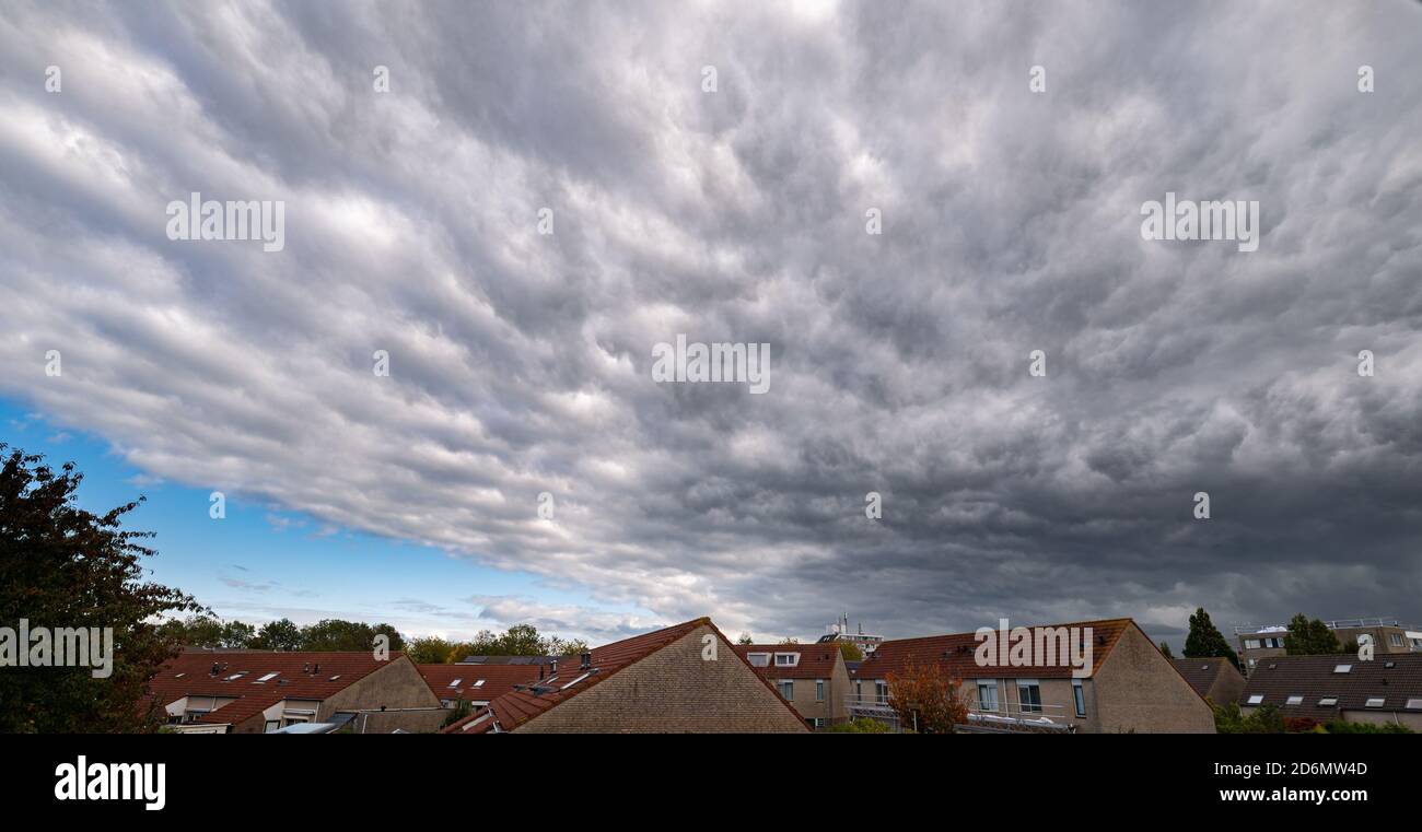 Dramatic sky with mammatus or bubble clouds over a dutch town Stock Photo