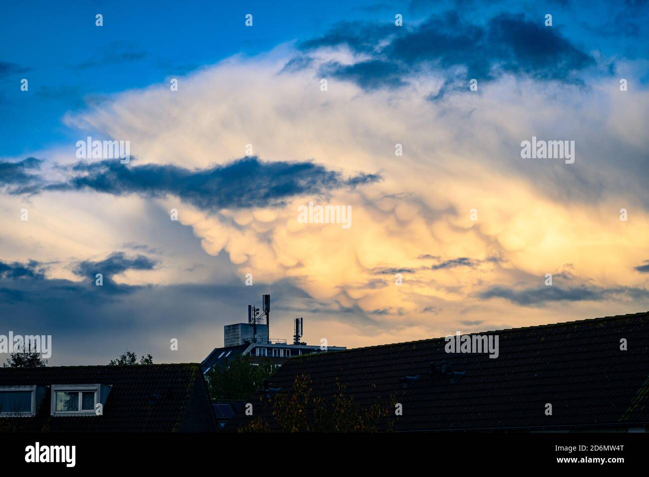Mammatus clouds below the anvil of a thunderstorm are illuminated by the light of the setting sun. Stock Photo