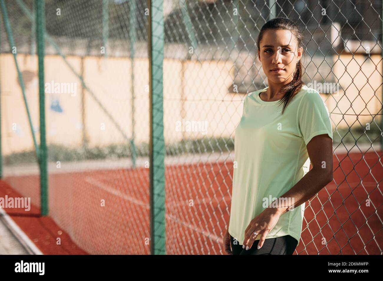Woman having break during workout near chain link fence Stock Photo