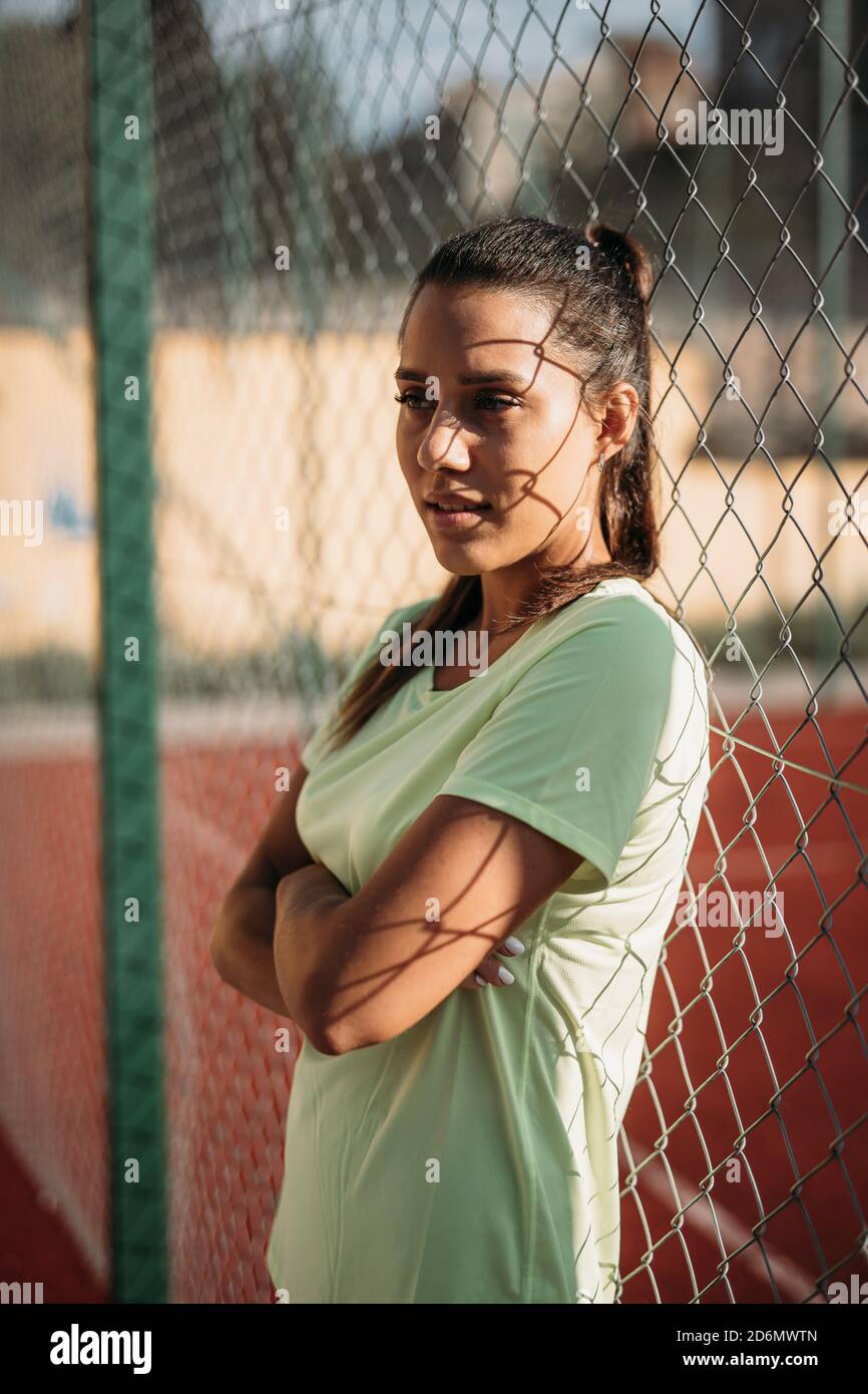 Attractive brunette leaning on chain link fence outdoors Stock Photo