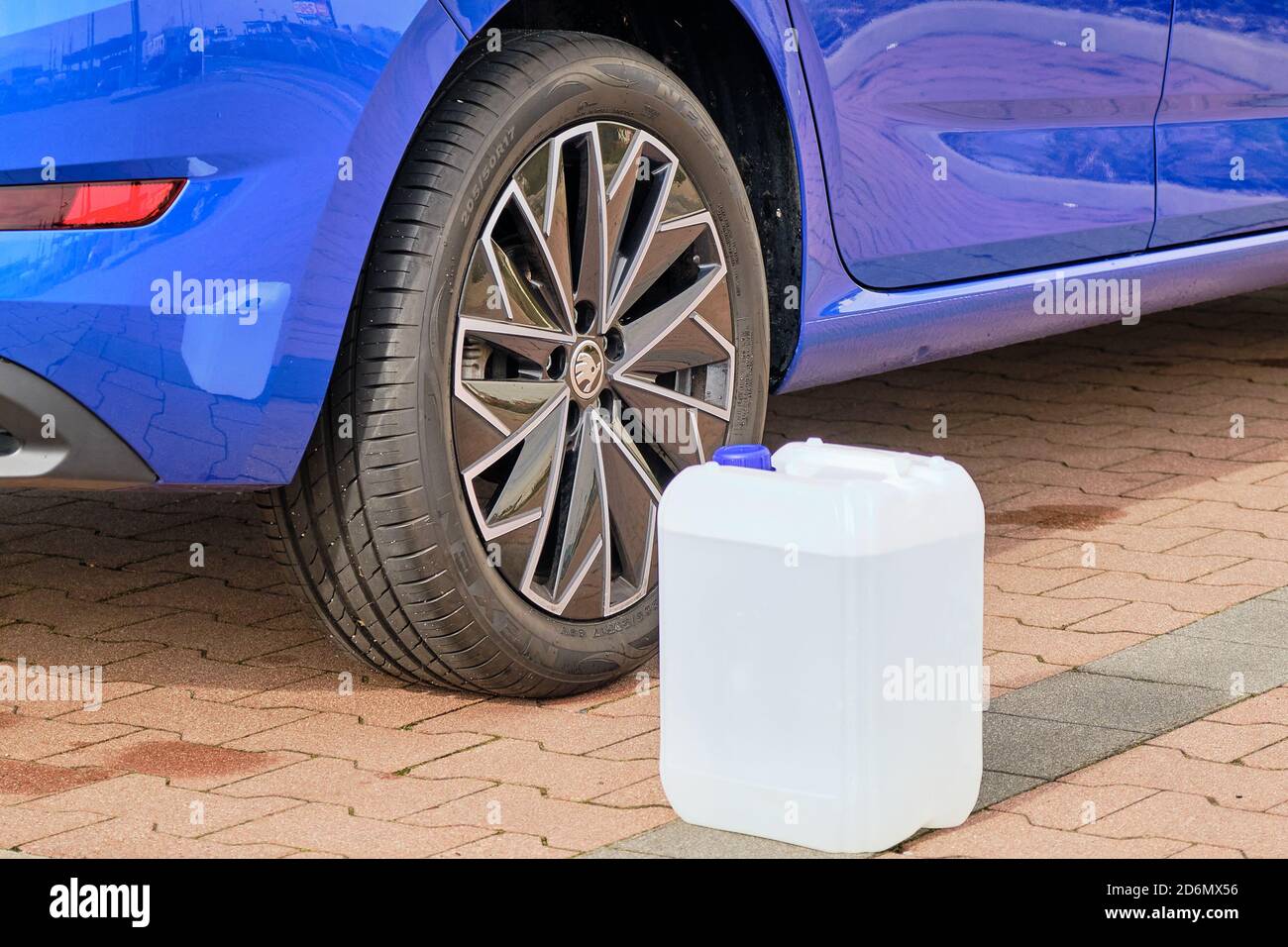 Close up a white canister with a diesel exhaust fluid near the wheel of blue Skoda automobile. Ad Blue liquid for reduction of air pollution, October Stock Photo