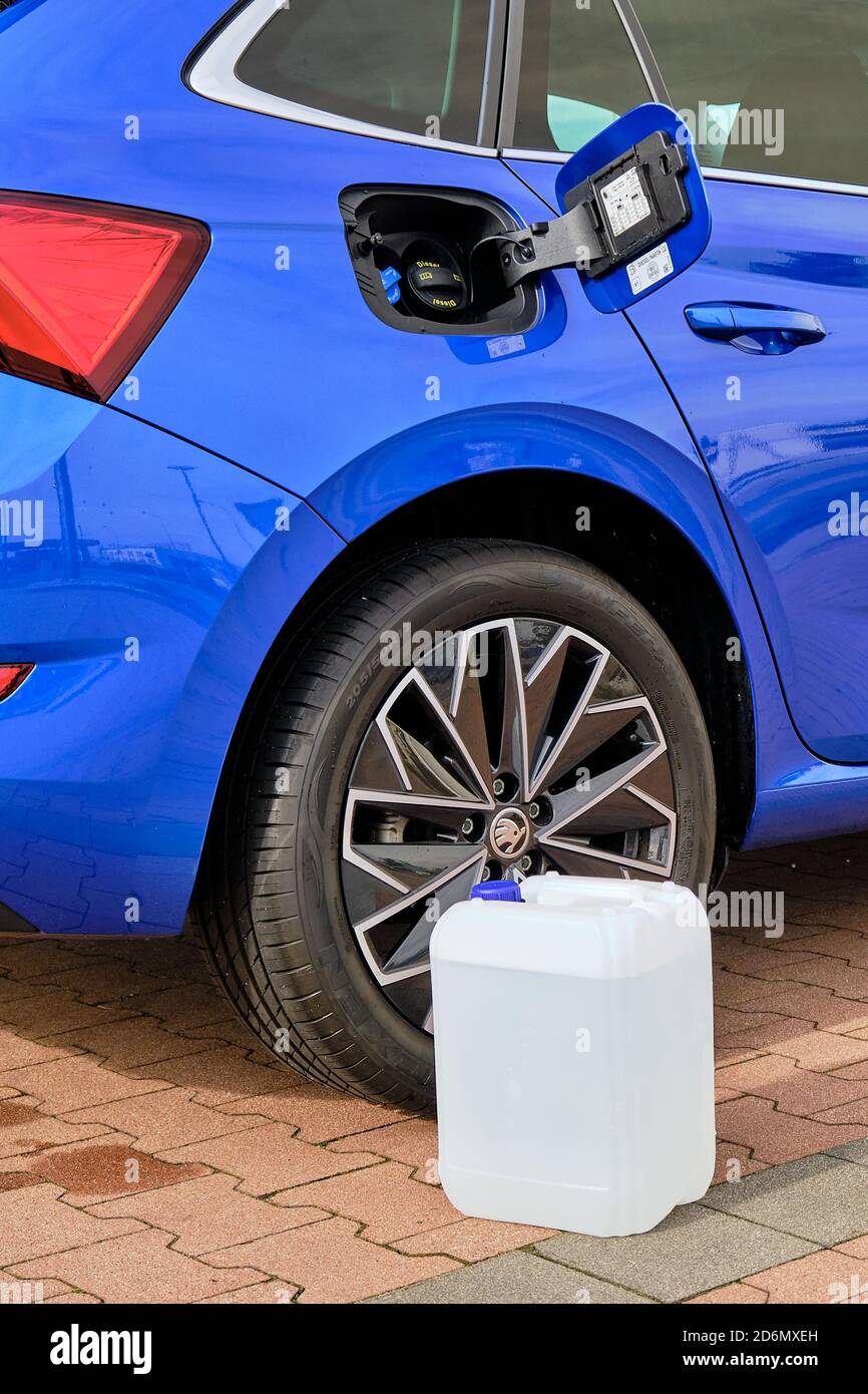 Close up a white canister with a diesel exhaust fluid near the wheel of blue Skoda automobile. Ad Blue liquid for reduction of air pollution, October Stock Photo