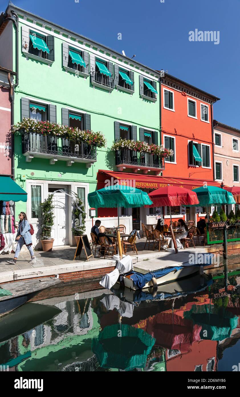 Tourists sitting outside brightly coloured Ristorante Pizzeria Principe - Al Campiello del Principe canalside restaurant in Burano, Venice, Italy Stock Photo