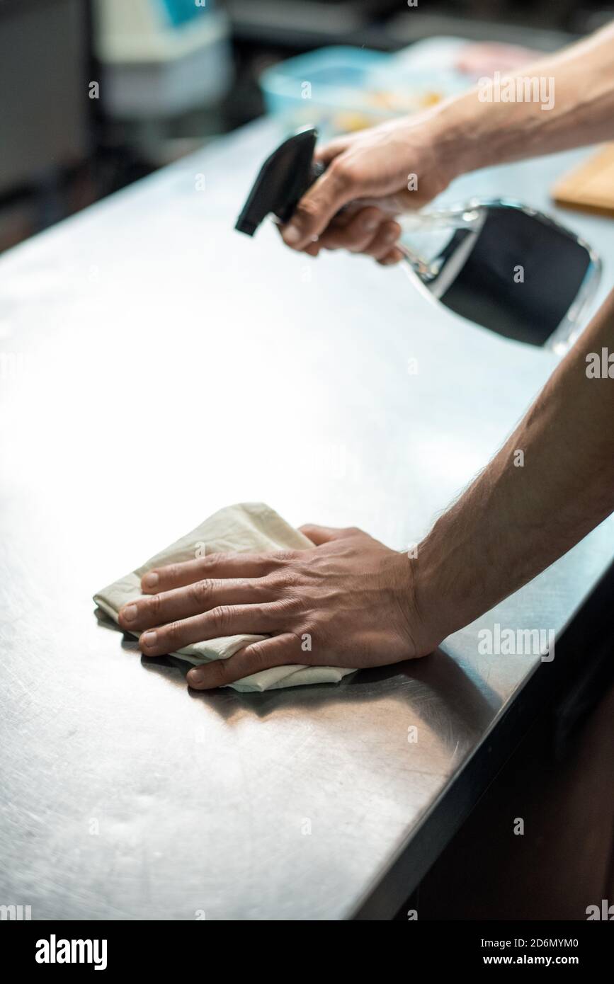 Hands of contemporary chef of restaurant spraying sanitizer on kitchen
