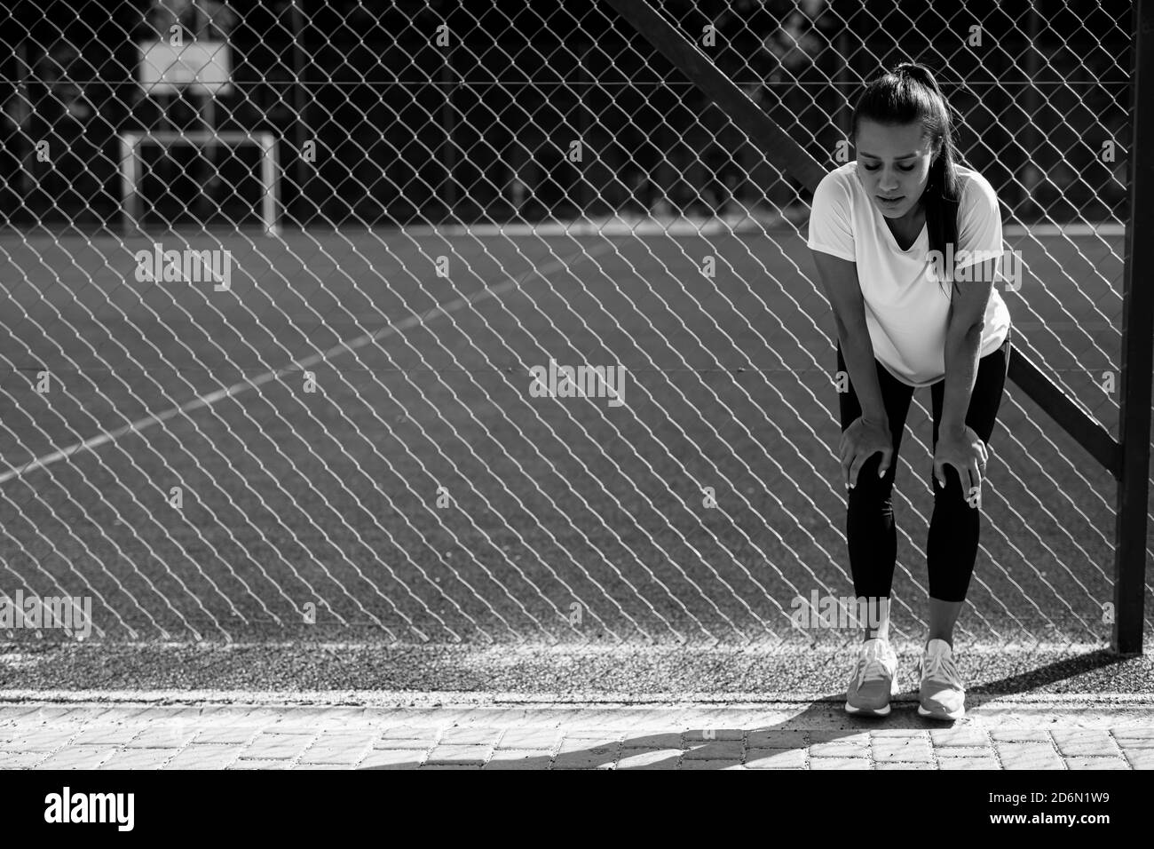 Exhausted woman in sport clothing resting at stadium Stock Photo