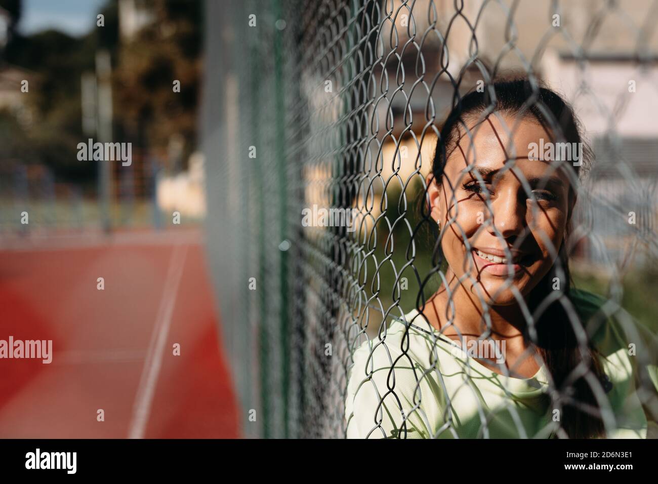 Active female looking aside through chain link fence Stock Photo