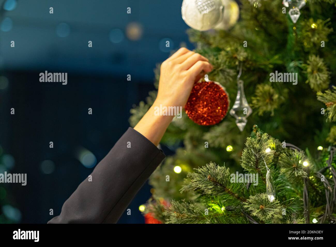 woman hand decorates a Christmas tree with red ball toy Stock Photo - Alamy