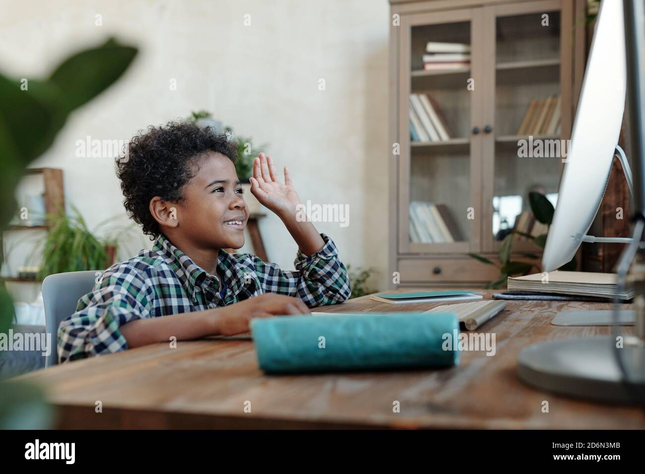 Happy little schoolboy sitting in front of computer monitor during ...