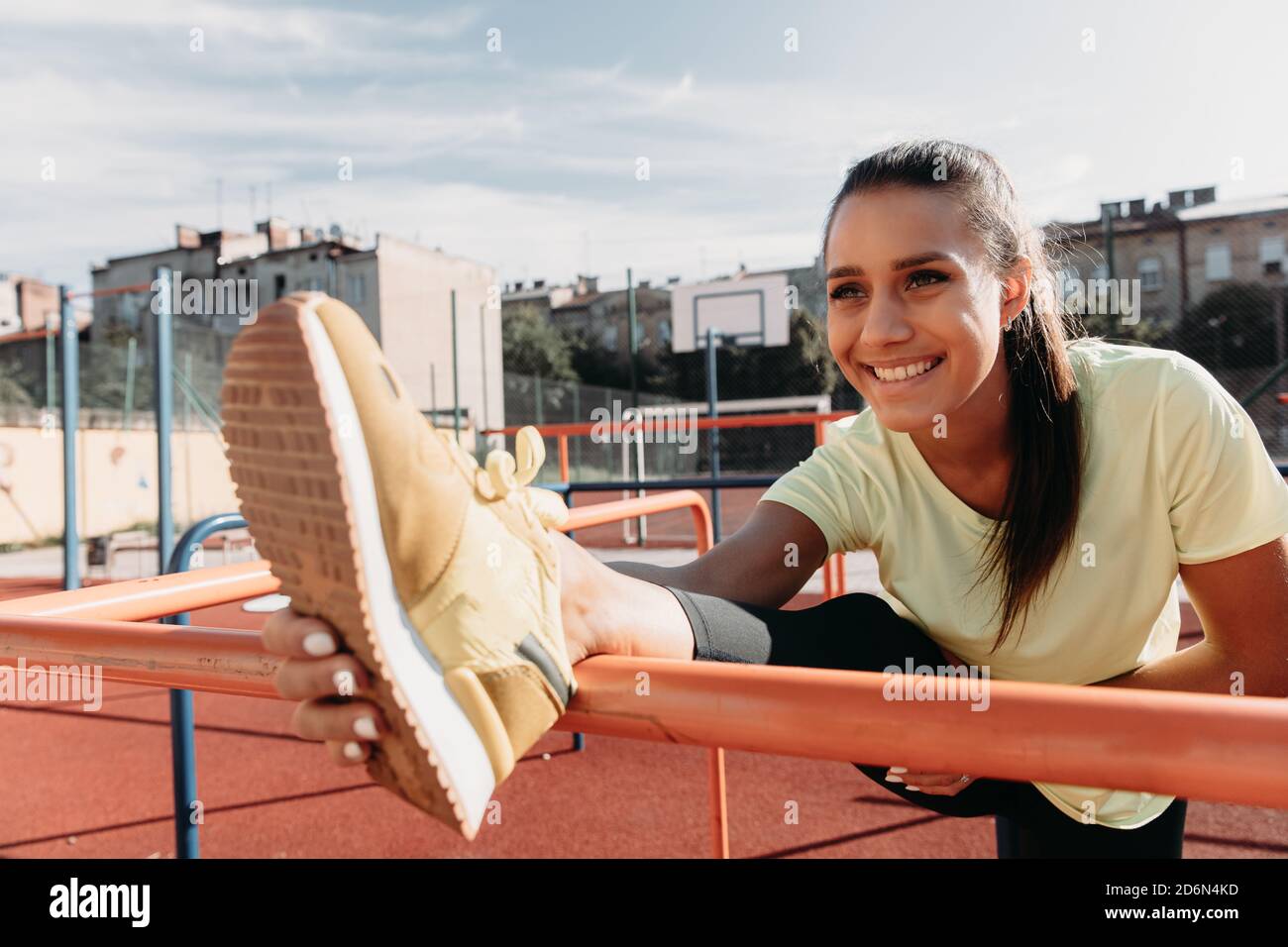 Cheerful woman stretching legs on sport ground Stock Photo