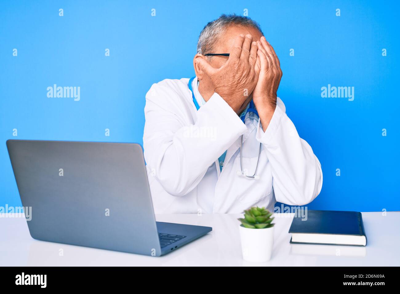 Senior handsome man with gray hair wearing doctor uniform working using ...