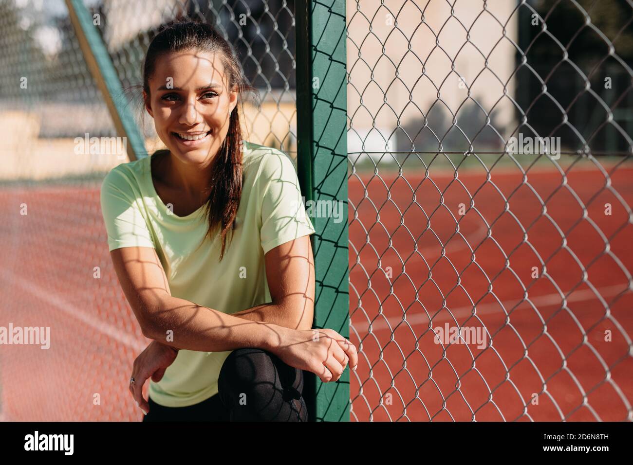 Portrait of sportswoman standing near chain link fence Stock Photo