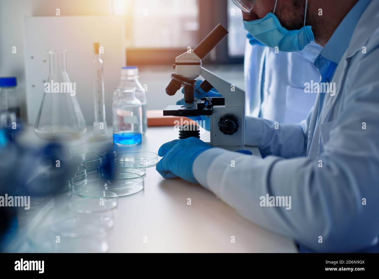 Doctor in the laboratory analyzes samples under a microscope. Pharmaceutical treatment concept. Stock Photo